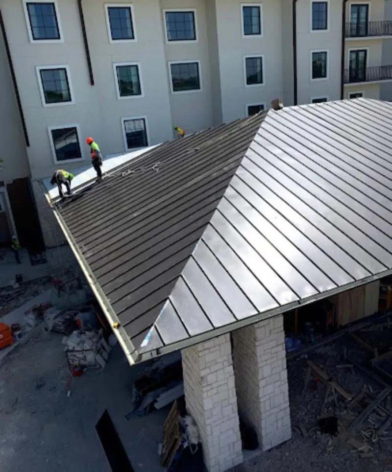 Crew installing standing seam metal roof panels on a commercial project in Grand Prairie